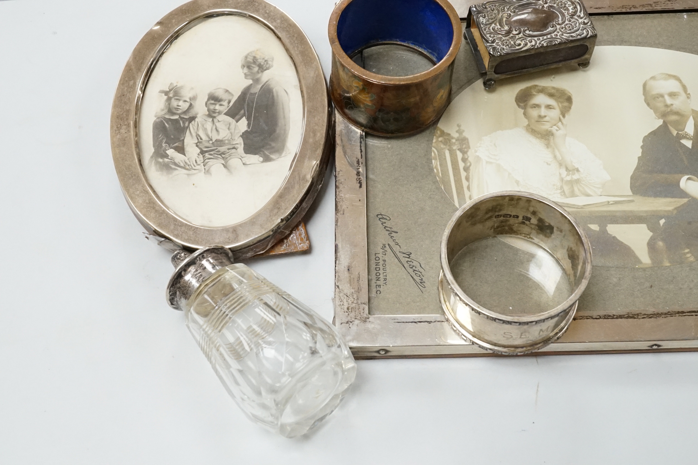 Two George V silver mounted photograph frames including oval, an Indian white metal flower holder and other items including silver napkin rings and a matchbox sleeve.